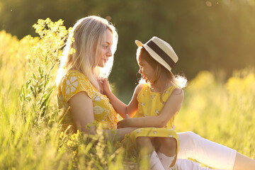 Mother and her little daughter are having fun in a summer meadow with yellow flowers. Happy family in summer. Concept of healthy family without allergies. . High quality photo