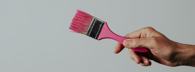 man grabs a paintbrush with pink paint, banner