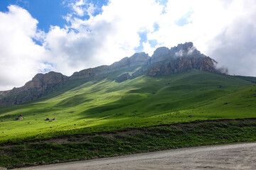 The landscape of the green Aktoprak pass in the Caucasus, the road and the mountains under gray clouds. Kabardino-Balkaria, Russia