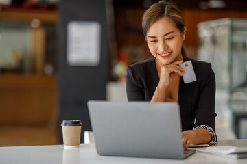 Asian businesswoman use credit cards and laptop computers mobile smartphones for payments and...