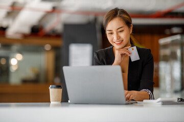 Asian businesswoman use credit cards and laptop computers mobile smartphones for payments and online shopping, Online shopping, digital banking, E-commerce credit card concept.