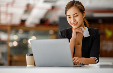 Asian businesswoman use credit cards and laptop computers mobile smartphones for payments and...