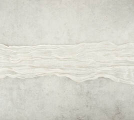 Wrinkled gauze fabric on light grunge stone background. Cotton gauze fabric cloth on stone tile surface with copy space.