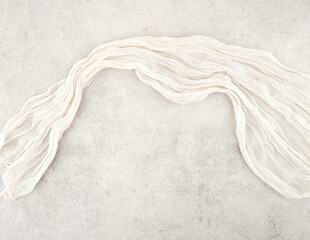 Wrinkled gauze fabric on light grunge stone background. Cotton gauze fabric cloth on stone tile surface with copy space.