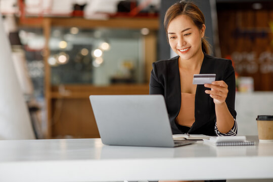 Asian businesswoman use credit cards and laptop computers mobile smartphones for payments and online shopping, Online shopping, digital banking, E-commerce credit card concept.