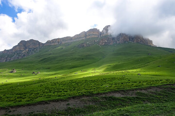 The landscape of the green Aktoprak pass in the Caucasus, the road and the mountains under gray clouds. Kabardino-Balkaria, Russia