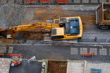 construction equipment excavates a city street to improve the wastewater infrastructure. Top View. Selective Focus Machine