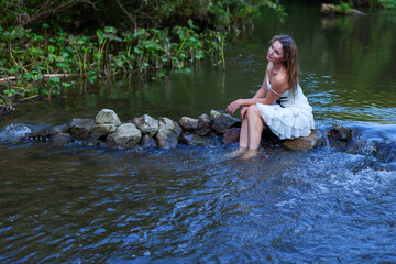 woman in white dress splashes in the river