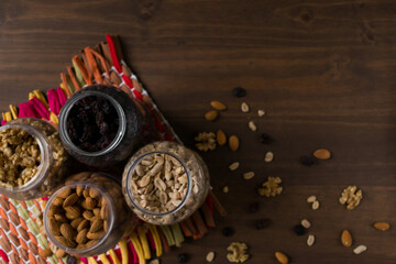 Bodegón de envases con frutos secos, nueces, almendras, maní y pasas de uva. Frascos transparentes con tapas amarillas. Naturaleza muerta. 