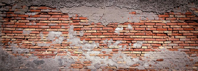 Urban rustic background. Panoramic view of the brickwork. Brick wall with peeling concrete plaster as background.