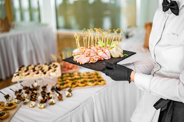 woman hands of a waiter prepare food for a buffet table in a restaurant