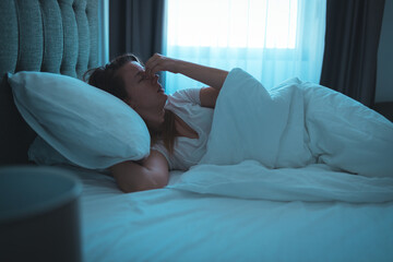 Photo of a young woman lying in bed at night, wide awake with a case of insomnia. Sleep disorder,...