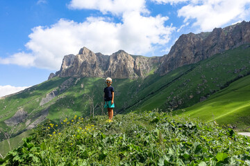 A boy on the background of the green landscape of the Aktoprak pass in the Caucasus. Russia, June...