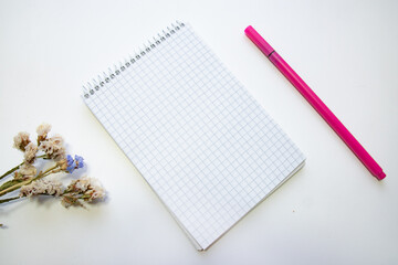 Notepad, marker and flowers on a white background. concept idea