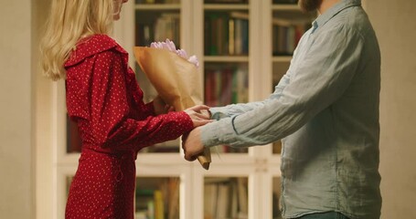Happy couple at romantic date. Man giving a woman a bouquet of flowers.