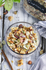 Vegan keto Granola made with pecans, hazelnuts, unsweetened coconut, sunflower seeds, pepita seeds and sweetened with erythritol. Served with low carb almond milk. Top view over a white wooden table.