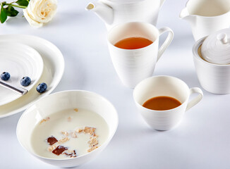 Breakfast milk cereal and tea with blueberries in white cutlery