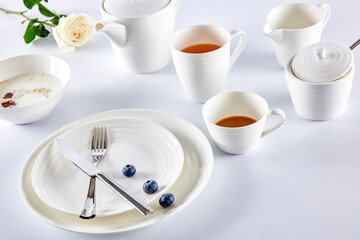 Breakfast milk cereal and tea with blueberries in white cutlery