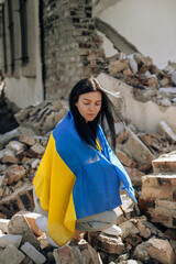 No war in Ukraine. the girl is wrapped in the Ukrainian flag. background destroyed house