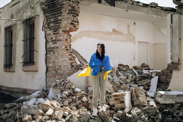No war in Ukraine. the girl is wrapped in the Ukrainian flag. background destroyed house