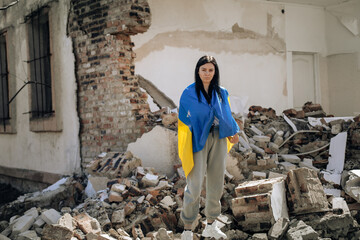 No war in Ukraine. the girl is wrapped in the Ukrainian flag. background destroyed house - 496118050