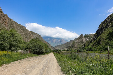 Fototapeta na wymiar The landscape of the green Aktoprak pass in the Caucasus, the road and the mountains under gray clouds. Kabardino-Balkaria, Russia