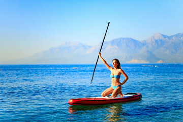 Woman paddling on sup board with mountains on background
