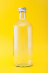 Empty glass bottle close up on a yellow background