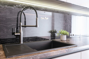 black sink, metal faucet in the new kitchen