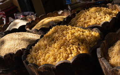 Assorted pasta and groats on the market counter. Wooden bowls with various cereals at the food...