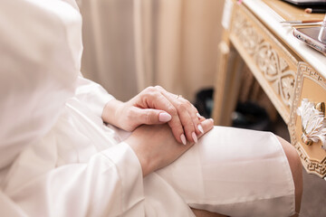 bride's hands on the wedding dress in the morning