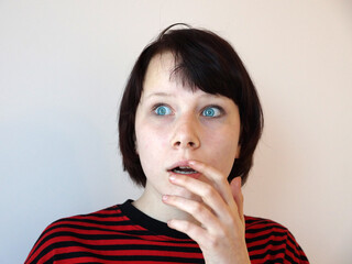 portrait of a surprised scared teen girl with blue eyes on a white background