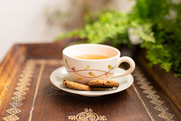 Tea cup placed on an old wooden table with green leaves background with soft sunlight in the morning, giving a fresh feeling Relaxing and calm.
