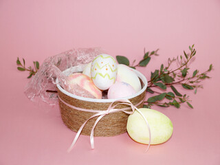 easter concept, decorative bowl with colored eggs and a spring branch on a pink background, easter card