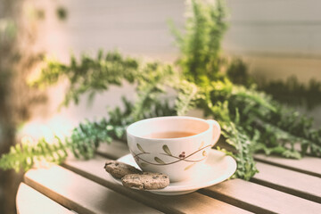 Tea cup placed on an old wooden table with green leaves background with soft sunlight in the morning, giving a fresh feeling Relaxing and calm.