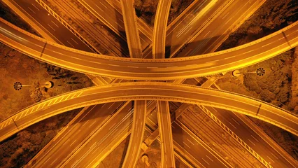 Fotobehang Snelweg bij nacht Aerial drone long exposure night shot of elevated urban junction motorway with light traffic and light trails  © aerial-drone