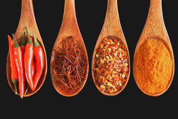 Vier braune Holzkochlöffel mit verschiedenen Formen des Chilis - der Peperoni darauf, schwarzer...