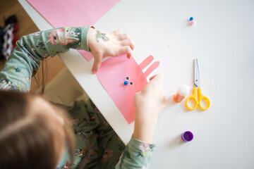 easter paper craft for kids. child girl making banny in kindergarten in spring