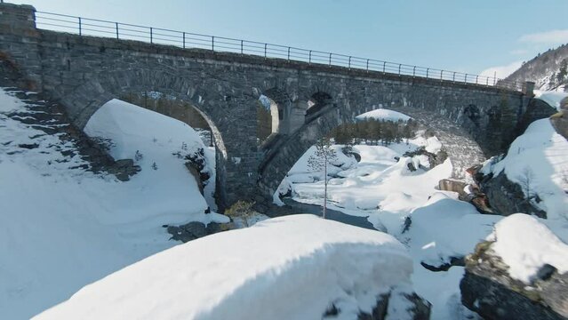 FPV fly under old stone bridge in winter wonderland of Norway. Extremely dangerous fly