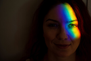 Close-up portrait of caucasian woman with ray of rainbow light on her face. 