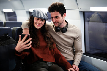 Loving couple travel by train. Happy woman and man talking while sitting in the train.