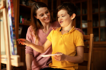 Mother and son painting at home. Little boy drawing with mom in living room.