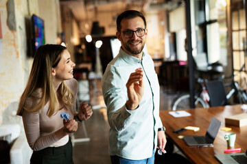 Young colleagues taking break after work. Happy young businessman and businesswoman playing darts in the office...