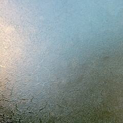 Background, texture. Frozen glass with the onset of cold weather. View through the ice layer of the blue sky.