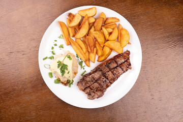 surf and turf - fried fish dish with grilled steak and potatoes top view over wooden table