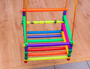 Children's colored swing in the apartment close-up on the background of the floor