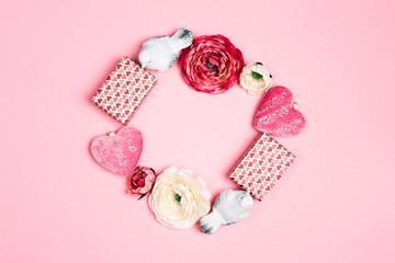 Romantic round frame of gifts, flowers, birds and decorative hearts on pink background. Place for text, top down composition.