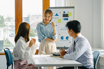 Obraz premium Young Asian businesswoman giving presentation to colleagues in board room.