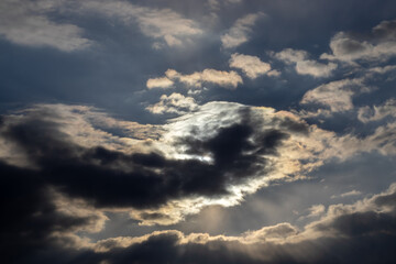 beautiful spring sky, covered with big clouds. extremely amazing, dramatic and apocalyptic sky and the sun and sunny rays. the sun is shining through dark clouds. sunshine. sunset