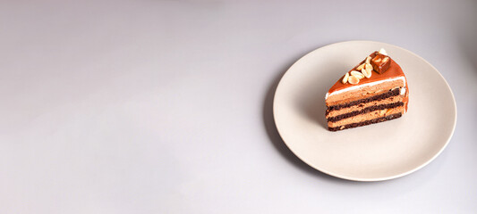 caramel cake decorated peanuts served on beige plate on beige background. banner